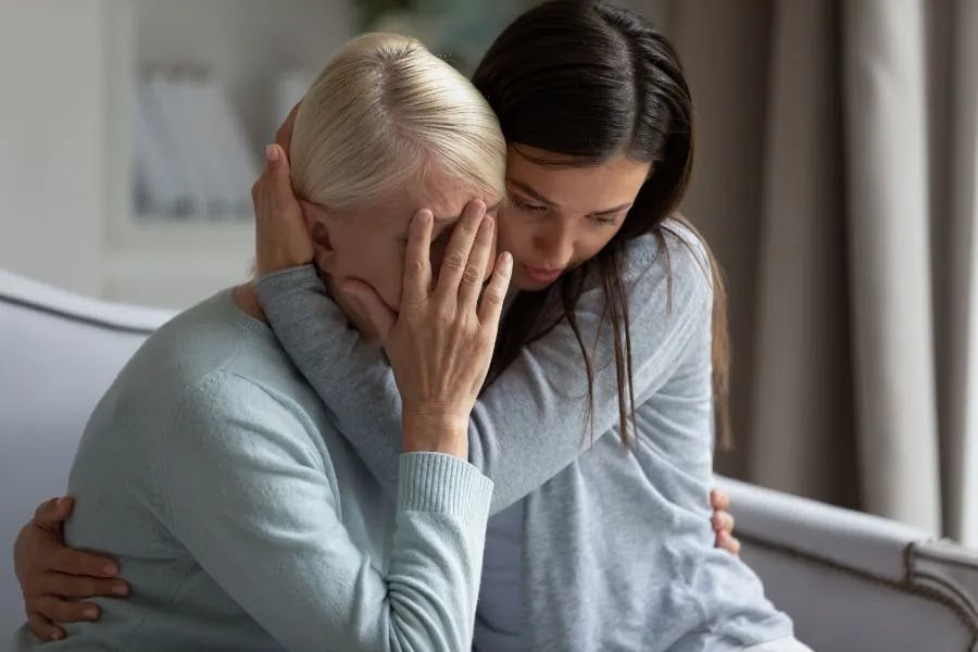 old lady crying and being hugged by a woman